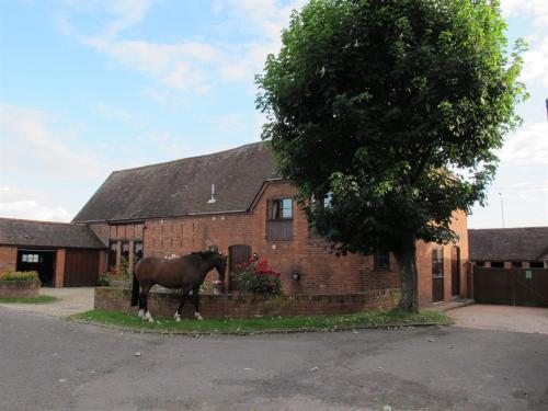 a horse standing in front of a brick house at Bluebell Farm in Upton upon Severn