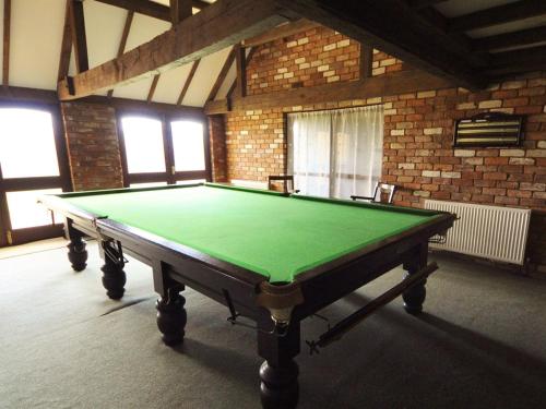 a green pool table in a room with a brick wall at Bluebell Farm in Upton upon Severn