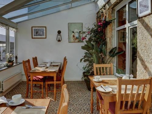 a dining room with tables and chairs and a window at Bosavern House in St. Just