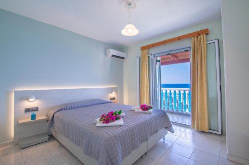 una camera da letto con un letto fiorito e un balcone di Baywatch Apartments on the Beach ad Amoudi