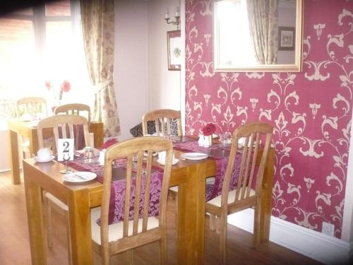 a dining room table and chairs with a purple wall at The Broadfield in Bridlington