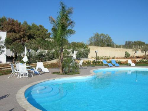 a swimming pool with chairs and a table and a palm tree at Itaca Residence Marsala in Marsala