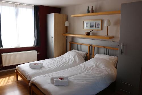 2 Betten in einem Hotelzimmer mit weißer Bettwäsche in der Unterkunft Brussels BnB in Brüssel