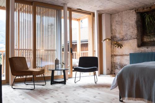 two chairs and a bed in a room with windows at TREMONDI - Boutique BnB in Quarten