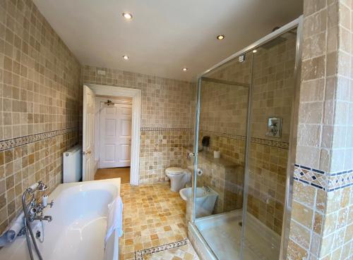 a bathroom with a shower and a tub and a toilet at Colwick Hall Hotel in Nottingham