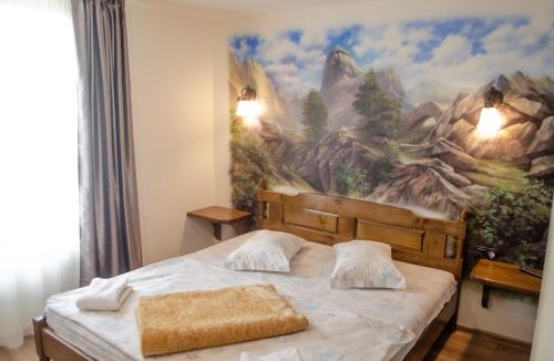 a bedroom with a bed with a painting on the wall at Pensiunea Hubertus in Bistriţa