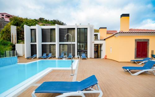 a villa with a swimming pool and blue lounge chairs at Hotel Solar Bom Jesus in Santa Cruz