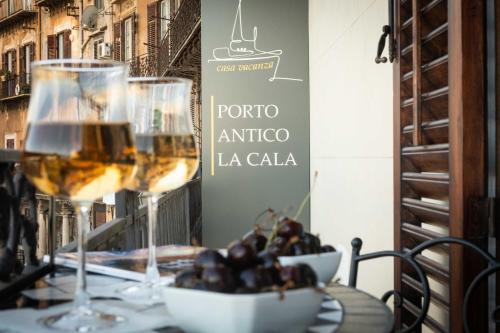 een tafel met twee glazen wijn en een kom druiven bij Camera Vento Porto Antico La Cala in Palermo