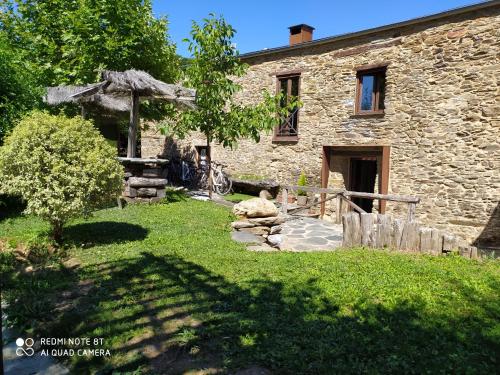 une maison en pierre avec un jardin en face dans l'établissement Albergue Atrio, à Tríacastela