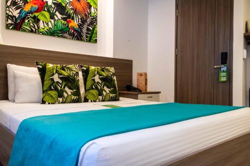 a bedroom with a large bed with a blue blanket at Lleras Green Hotel in Medellín