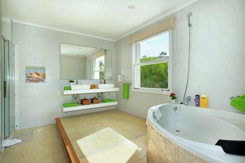 baño blanco con bañera y ventana en Beach Villa Can Ros, en Puerto Pollensa