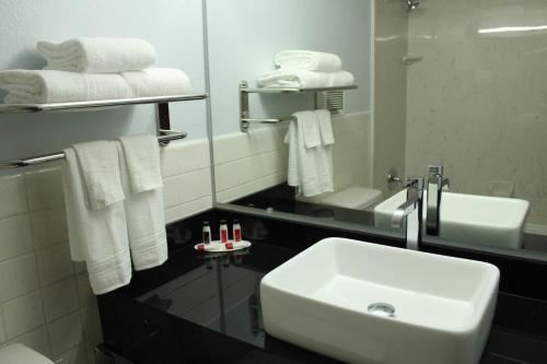 a bathroom with a sink and a mirror and towels at Travelodge by Wyndham Water's Edge Hotel - Racine in Racine