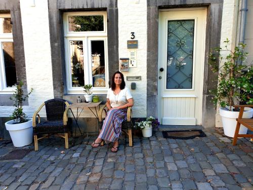 a woman sitting at a table in front of a house at Het Begijnhof Tongeren Center in Tongeren