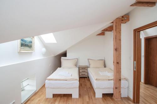 a attic room with two beds and a ladder at Pivovar Řevnice in Řevnice