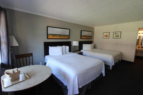 a hotel room with two beds and a table at At Home Inn - Pensacola in Pensacola