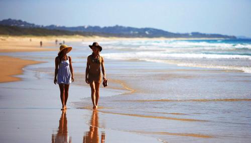 a man and woman walking on the beach at Ramada By Wyndham Marcoola Beach in Marcoola