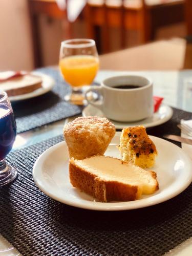 a plate with bread and a cup of coffee and orange juice at Hotel Somensi in Bento Gonçalves