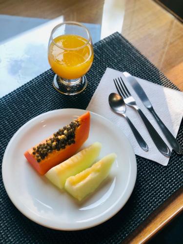 a plate of food with fruit and a glass of orange juice at Hotel Somensi in Bento Gonçalves