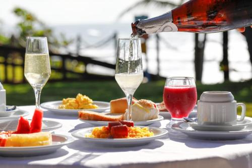 een tafel met borden en glazen wijn bij Pousada Ecoporto in Porto De Galinhas