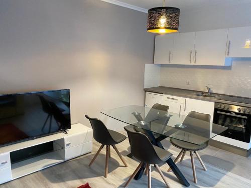 een keuken met een glazen tafel met stoelen en een televisie bij Napsugár Apartmanház in Harkány