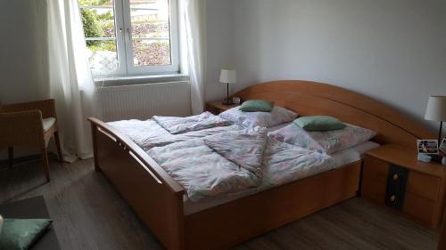 Schlafzimmer mit einem Bett mit einem Kopfteil aus Holz und einem Fenster in der Unterkunft Ferienwohnung Seeburger See in Seeburg