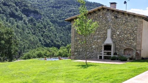 a stone building with a swimming pool in a grass field at Pujolís in Santa Cecilia de Voltregá