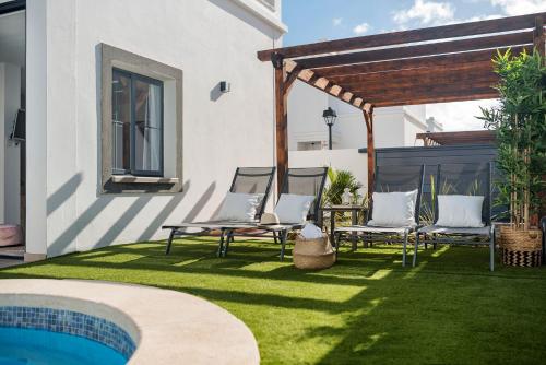 a backyard with chairs and a pergola and a pool at Villa palmera jacuzzi in Yaiza
