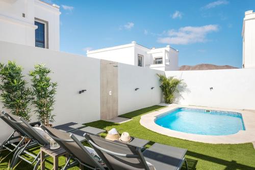 a patio with chairs and a swimming pool at Villa palmera jacuzzi in Yaiza