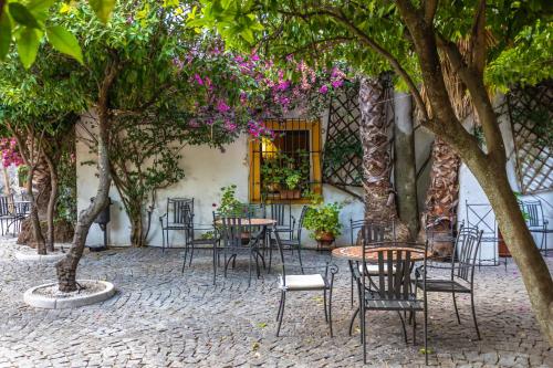 a patio with tables and chairs under trees at Hotel Sao Joao De Deus by RIDAN Hotels in Elvas