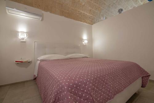 a bedroom with a bed with a purple comforter at Nivis Avis in Polignano a Mare