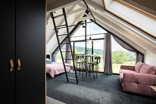 a room with a ladder and a table and a couch at Bieszczadzka Stodoła in Ustrzyki Dolne
