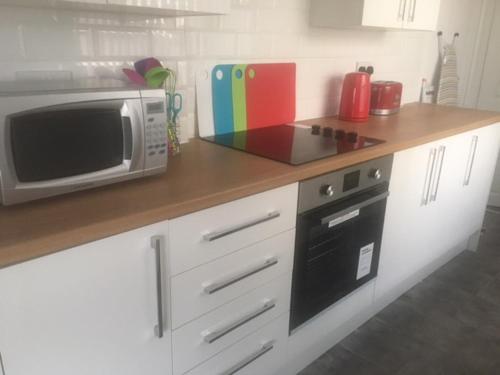 a kitchen counter with a microwave and a stove at Townhouse @ Minshull New Road Crewe in Crewe