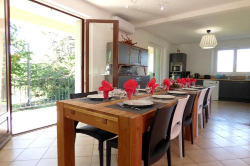 une longue table en bois avec des chaises et des serviettes rouges dans l'établissement Gites Bel Air de Rosette, à Bergerac