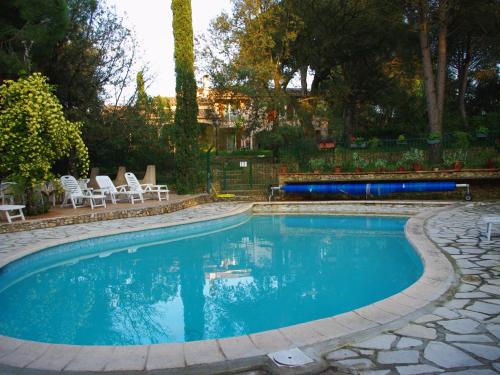 a swimming pool with two chairs and a bench in a yard at Les Chambres d'Hotes au Bois Fleuri in Roquebrune-sur-Argens