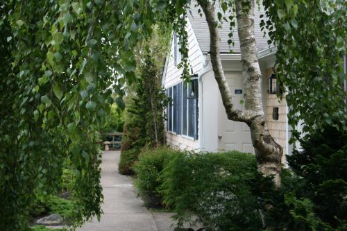 a sidewalk next to a white house with trees at Pleasant Bay Village Resort in Chatham