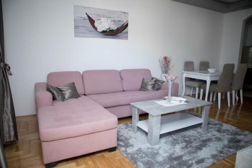 een woonkamer met een roze bank en een tafel bij Oasis of Peace in Trebinje