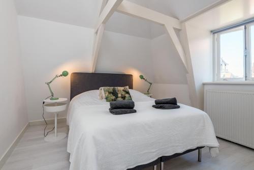 a white bedroom with a large white bed with pillows at Charming Apartments in Alkmaar