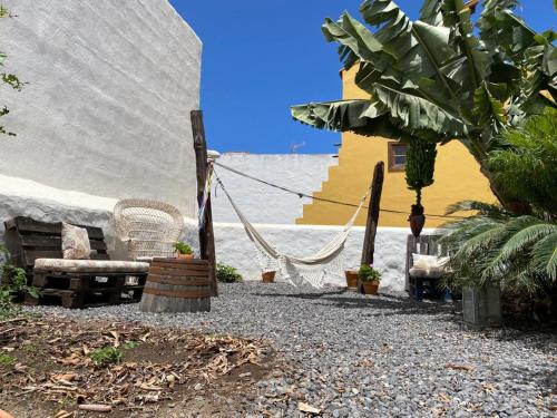 a patio with a hammock and chairs in a yard at Casa emblemática Buenavista del Norte in Buenavista del Norte