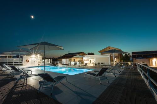 una piscina con sillas y sombrillas por la noche en Ca' Mira - Room&Breakfast en Savio di Ravenna