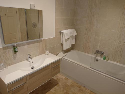 a bathroom with a sink and a tub and a mirror at Broom Hall Country Hotel in Saham Toney