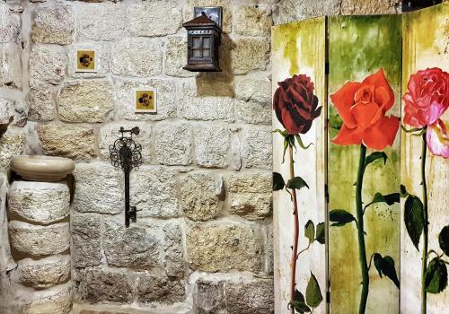 a stone wall with a lamp and flowers on it at 19th Century Magical House in Galilee in ‘Eilabūn