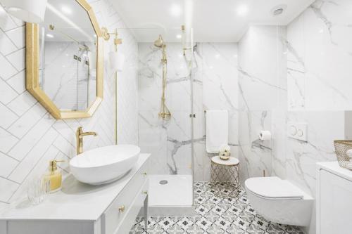 La salle de bains blanche est pourvue d'un lavabo et de toilettes. dans l'établissement Apartament Golden Place 2, à Cracovie