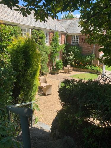 a garden with chairs in front of a house at Boscundle Manor in St Austell