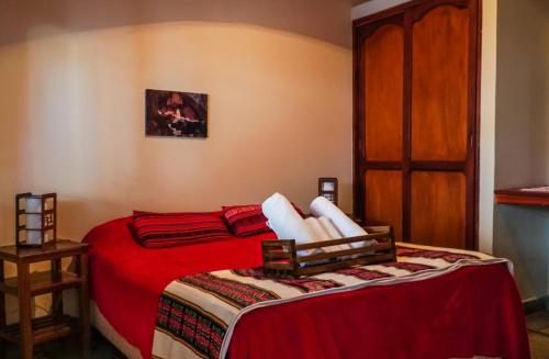 a bedroom with a bed with red sheets and a door at Azul Humahuaca Hostal in Humahuaca