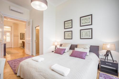 a bedroom with a large white bed with purple pillows at MODERNIZED Unique Huge Central Apartment On 135sqm in Budapest