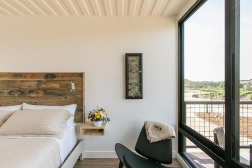 a bedroom with a bed and a chair and a window at Geneseo Inn in Paso Robles