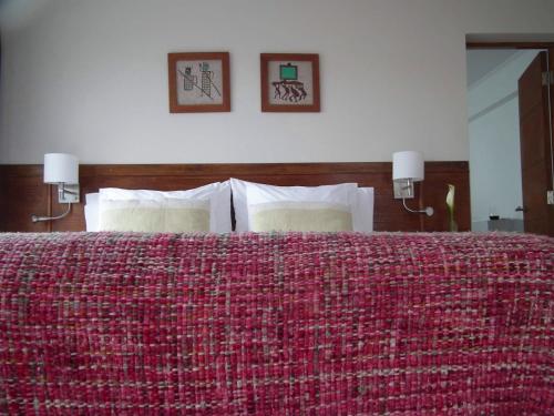 a bedroom with a red bed with two pictures on the wall at Hotel K in Bahia Inglesa