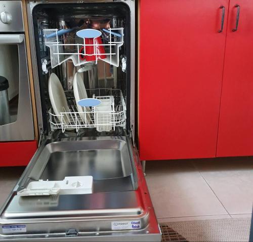 a dishwasher with dishes in it next to a red cabinet at Planinska kuća sa dvorištem in Zlatibor
