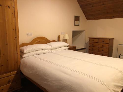 a bedroom with a large white bed and a dresser at Cosy holiday home, Scalloway, Shetland. in Scalloway