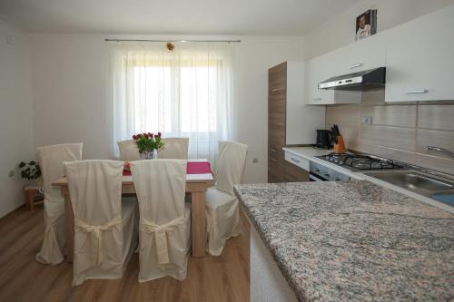 eine Küche mit einem Tisch mit Stühlen und einer Theke in der Unterkunft Apartman Lucija & Luka in Otočac